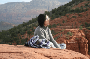 Man meditating outdoors on the rocks.